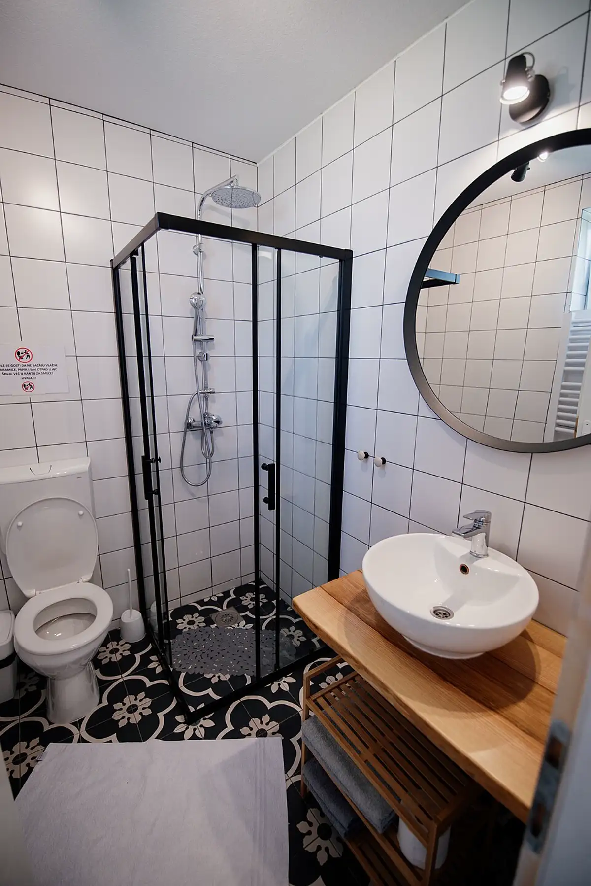 Baño renovado con ducha y espejo redondo